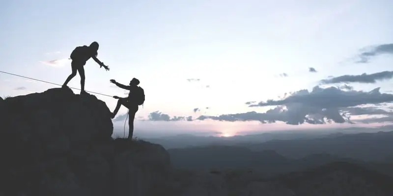 Find a Good Financial Advisor in Omaha 1 mountain climber giving hand to help another up. Symbolizes our guidance to clients as a financial advisor in omaha