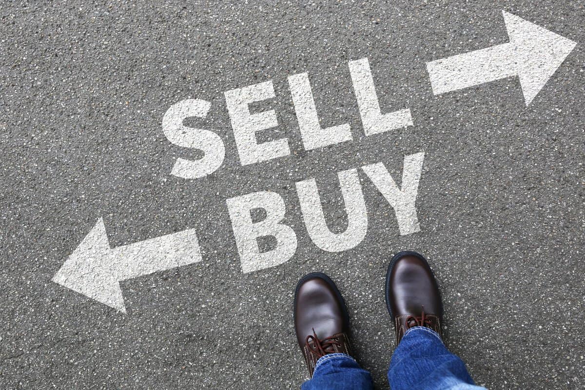 Directions on pavement reading "Buy" to the left and "Sell" to the right. illustrates confusion of sunk cost fallacy
